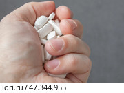 Мужская рука крупным планом сжимает в кулаке горсть крупных белых таблеток. Стоковое фото, фотограф Валерий Елистратов / Фотобанк Лори