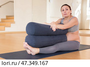 Pregnant woman practices yoga with roll in hall. Стоковое фото, фотограф Татьяна Яцевич / Фотобанк Лори