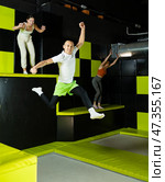 Cheerful young man jumping in modern indoor trampoline park. Стоковое фото, фотограф Яков Филимонов / Фотобанк Лори