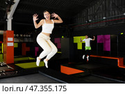 Cheerful young girl jumping in indoor trampoline arena. Стоковое фото, фотограф Яков Филимонов / Фотобанк Лори