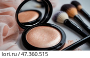 Cosmetics display featuring shiny bronzer alongside professional makeup brushes and soft fabric. Стоковое AI-изображение, AI-художник Сергей Толмачёв / Фотобанк Лори