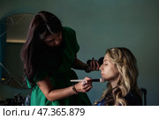 Makeup Artist Creating a Flawless Look on Client Inside a Chic Indoor Setting. Стоковое фото, фотограф Aleksandr Golubev / Фотобанк Лори