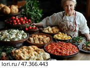 An elderly woman in a cozy kitchen, with a warm smile, dressed in a white blouse and a floral apron, stands at a wooden table set with a variety of delicious home-cooked dishes. In front of her are a variety of dishes: stewed vegetables in tomato sauce, dumplings with herbs, fresh tomatoes, potatoes, baked meat with herbs, ruddy buns and pies, herbs and spices. Everything is served in a rustic style, on ceramic and wooden dishes. The atmosphere is warm, welcoming, full of love and care, like at a family holiday. Стоковое AI-изображение, AI-художник Анна Кривицкая / Фотобанк Лори