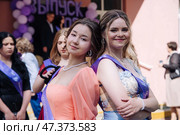 Female graduates wearing colorful sashes standing together, smiling and celebrating academic success during commencement ceremony. Стоковое фото, фотограф Mikhail Davidovich / Фотобанк Лори