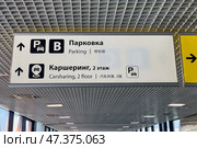 Информационные указатели в аэропорту Шереметьево, Москва. White and yellow signs at Sheremetyevo Airport, exit to Terminals B, C. Exit to Parking zone. Convenient informational navigation and markings for tourists and visitors. Редакционное фото, фотограф Ирина Михайличенко / Фотобанк Лори