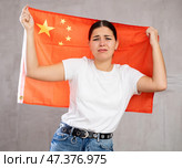 Sad young woman holding China flag against unicoloured background. Стоковое фото, фотограф Яков Филимонов / Фотобанк Лори