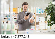 Man in pharmacy scans QR code on emollient cream product. Стоковое фото, фотограф Яков Филимонов / Фотобанк Лори