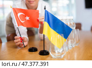 Unrecognizable girl sets midget flags of Ukraine and Turkey before international negotiations. Стоковое фото, фотограф Яков Филимонов / Фотобанк Лори