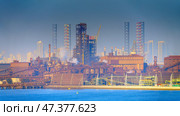 Manama, Bahrain- Jan 08 2024, Panoramic view of the industrial port buildings, constructions, the skyscrapers of Manama are visible in the distance, in the daytime, Manama, Bahrain. Редакционное фото, фотограф Сергей Богомяко / Фотобанк Лори