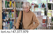 Mature woman chooses an ironing board in a store with household chemicals. Стоковое видео, видеограф Яков Филимонов / Фотобанк Лори