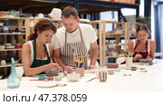 During master class, student paints clay vessel under guidance of male teacher. Стоковое видео, видеограф Яков Филимонов / Фотобанк Лори