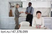 Sad middle-aged woman sitting at the kitchen table with her back to man and old woman quarreling together. Стоковое видео, видеограф Яков Филимонов / Фотобанк Лори