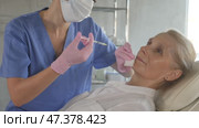 Old female patient lying on clinical chair undergoing face care procedure by injection method. Стоковое видео, видеограф Яков Филимонов / Фотобанк Лори