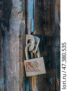 Rusty Padlock Securing Weathered Wooden Door. Vertical crop. Стоковое фото, фотограф Elena Grishina / Фотобанк Лори