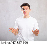 Disputing young man standing against background of grey unicolored wall. Стоковое фото, фотограф Яков Филимонов / Фотобанк Лори