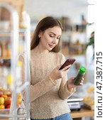 Female buyer checks suitability - scans QR code on seasonings herbs label in grocery store. Стоковое фото, фотограф Яков Филимонов / Фотобанк Лори