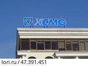 Вывеска и логотип XCMG (Xuzhou Construction Machinery Group Co., Ltd.) на крыше делового здания на фоне синего неба. Редакционное фото, фотограф Цибаев Алексей / Фотобанк Лори