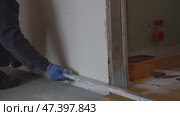 From the bottom of the floor, a male plasterer holds a metal rule in his hands and aligns the newly plastered wall. Стоковое видео, видеограф Darya Komarova / Фотобанк Лори