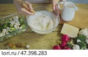 Creamy yoghurts and mayonnaise are whisked together in a deep bowl, before being used to prepare a rustic vegetable dish. Стоковое видео, видеограф Strunov David / Фотобанк Лори
