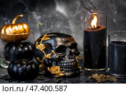 A mysterious black skull with golden roses and pumpkins for a Halloween or Day of the dead party on a black grunge background. Стоковое фото, фотограф Photojuli / Фотобанк Лори