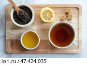Черный чай, мед, лимон, коричневый сахар и сухая заварка на подносе. Чай для чаепития. Стоковое фото, фотограф Тамара Селиванова / Фотобанк Лори