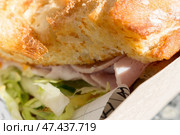 Сэндвич с вкуснейшим свежим хлебом с хрустящей корочкой и ветчиной в оберточной бумаге и картонном подносе, купленный на фуд-корте. Стоковое фото, фотограф Татьяна Васильева / Фотобанк Лори