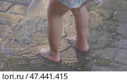 A cheerful child plays joyfully with water outside, feeling the coolness under bare feet. Стоковое видео, видеограф Olesia Kondrateva / Фотобанк Лори