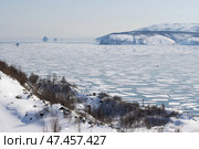 Весенний дрейф льдин в бухте Гертнера. Охотское море. Магадан, Магаданская область, Дальний Восток России. В морской бухте начал раскалываться и расходиться трещинами лёд. Вдали справа на льдинах видны автомобили рыбаков, которые унесло в море на отколовшихся льдинах. Чрезвычайная ситуация. Апрель. Стоковое фото, фотограф Андрей Степанов / Фотобанк Лори