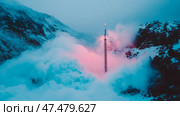 Otherworldly landscape: Snowy peaks and a tower shrouded in pink and cyan clouds. Стоковое AI-изображение, AI-художник Данила Большаков / Фотобанк Лори