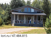Frame house in Scandinavian style. The landscape. Quiet rest. The concept of glamping and chalet rentals. Wooden house with a veranda in nature. (2024 год). Стоковое фото, фотограф Photojuli / Фотобанк Лори