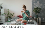 Student pauses studies to sip coffee, enjoying calm atmosphere. Open notebooks, highlighters, and planner nearby reflect well-organized study routine with moments for relaxation. Стоковое видео, видеограф Енваев Андрей / Фотобанк Лори
