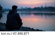 A Lone Mourner Sits Quietly by a River at Twilight, Whispering Prayers for the Martyrs of Karbala. Стоковое AI-изображение, AI-художник Sergey Grishin / Фотобанк Лори