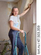 Woman Removing Wallpaper Smiling on Ladder. Стоковое фото, фотограф Кутина Татьяна / Фотобанк Лори