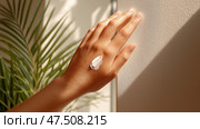 Female hand applying cream to arm in natural light with plant background. Женская рука наносит крем на руку при естественном освещении на фоне растений. Стоковое AI-изображение, AI-художник Katsiaryna Repich / Фотобанк Лори