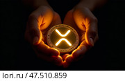 Hands holding glowing xrp coin against black background. Редакционное AI-изображение, AI-художник Андрей Бакусов / Фотобанк Лори