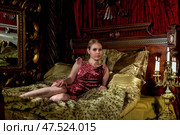 Elegant Figure Resting on a Richly Adorned Bed in an Opulent Indoor Setting. Стоковое фото, фотограф Aleksandr Golubev / Фотобанк Лори
