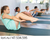 Girl perform boat asana - Paripurna navasana. Comprehensive hatha yoga class in mini group. Стоковое фото, фотограф Яков Филимонов / Фотобанк Лори