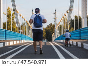 The bridge over the Kotorosl River to Damansky Island and people passing by. Yaroslavl, Russia. Редакционное фото, фотограф Photojuli / Фотобанк Лори