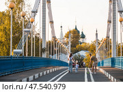 The bridge over the Kotorosl River to Damansky Island and people passing by. Yaroslavl, Russia. Редакционное фото, фотограф Photojuli / Фотобанк Лори