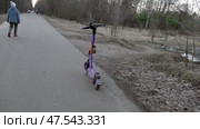 Электросамокат стоит на дорожке в лесу. Март. An electric scooter stands on a path in the forest. March. Редакционное видео, видеограф Горшков Александр / Фотобанк Лори