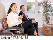 Serious-minded female candidate siting on chair and waiting for job interview in hallway. Стоковое фото, фотограф Яков Филимонов / Фотобанк Лори