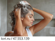 Woman washing her hair with shampoo in a bright bathroom during daytime. Женщина моет волосы шампунем в светлой ванной комнате в дневное время. Стоковое AI-изображение, AI-художник Katsiaryna Repich / Фотобанк Лори