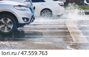 Splashing white vehicle sending water spray across urban roadway during bright daylight. Стоковое фото, фотограф Mikhail Davidovich / Фотобанк Лори