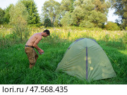 The man installs and assembles tourist tent in a camping in nature in the forest. Domestic tourism, active summer holidays, family adventures. Ecotourism, sport, hike. Стоковое фото, фотограф Ольга Симонова / Фотобанк Лори