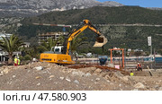 Budva,Montenegro-April 11,2025:Liebherr excavator operating at a beachside. Редакционное фото, фотограф Margarita Davchenko / Фотобанк Лори