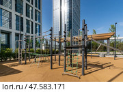 Modern playground equipment in an urban setting under clear blue skies. Surrounding tall buildings suggest a lively urban atmosphere. Стоковое фото, фотограф Алексей Климкин / Фотобанк Лори
