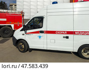 ANGARSK, IRKUTSK REGION, RUSSIA - April 08, 2025: Emergency vehicles on a city street. A red fire truck and a white ambulance near a crowded shopping mall Festival on sunny spring day. Редакционное фото, фотограф Виктория Катьянова / Фотобанк Лори