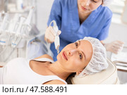 Young female client experiencing facial skin peeling using ultrasonic scrubber. Стоковое фото, фотограф Яков Филимонов / Фотобанк Лори