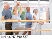 Male choreographer teaches elderly ballet lovers to stand in grand batman position. Стоковое фото, фотограф Яков Филимонов / Фотобанк Лори