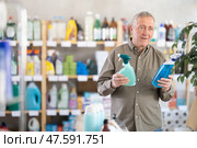 Senior man studies label and choose kitchen cleaner spray. Стоковое фото, фотограф Яков Филимонов / Фотобанк Лори